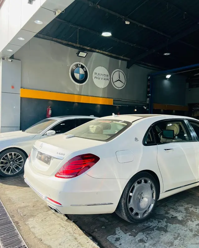 مرسيدس S600 بيضاء أمام شعارات BMW ورنج روفر ومرسيدس
