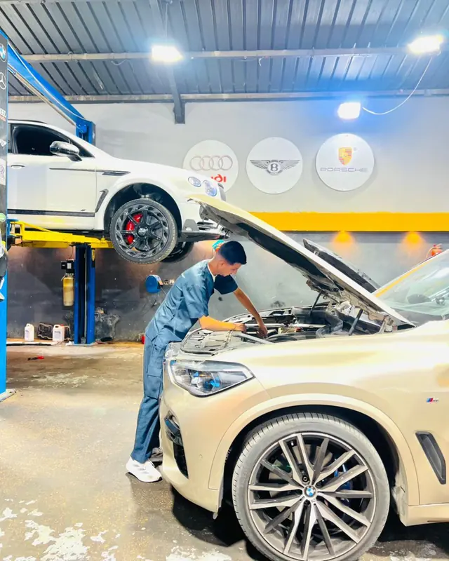فني يعمل على محرك BMW X5 وسيارة بنتلي على الرافعة