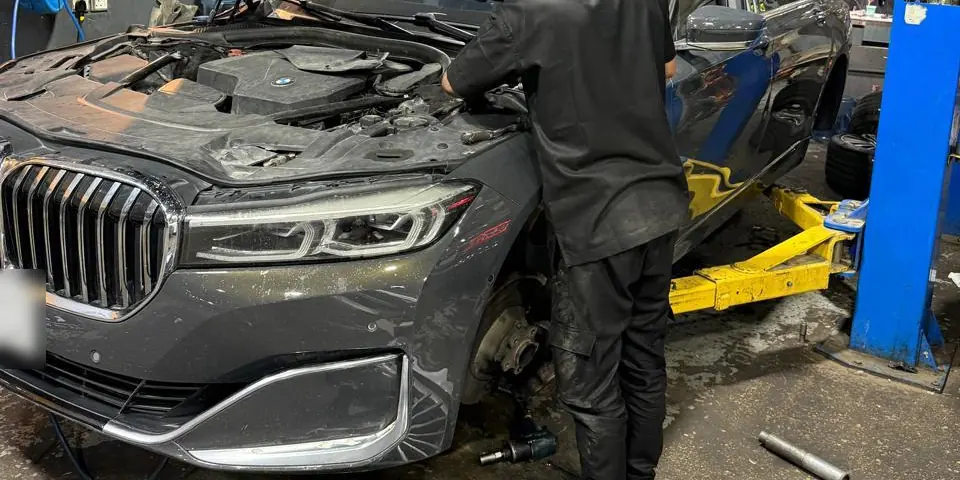 فني يعمل على عجلة وفرامل سيارة BMW الفئة السابعة بعد فك الإطار